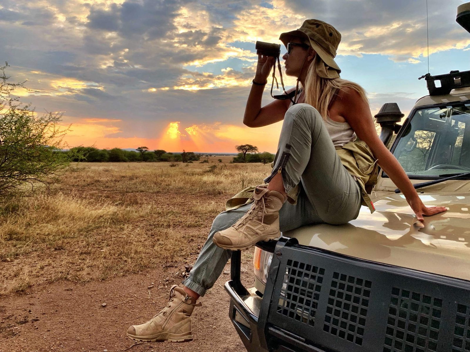 African safari luxury tours with a traveler observing the savanna from a safari vehicle at sunset